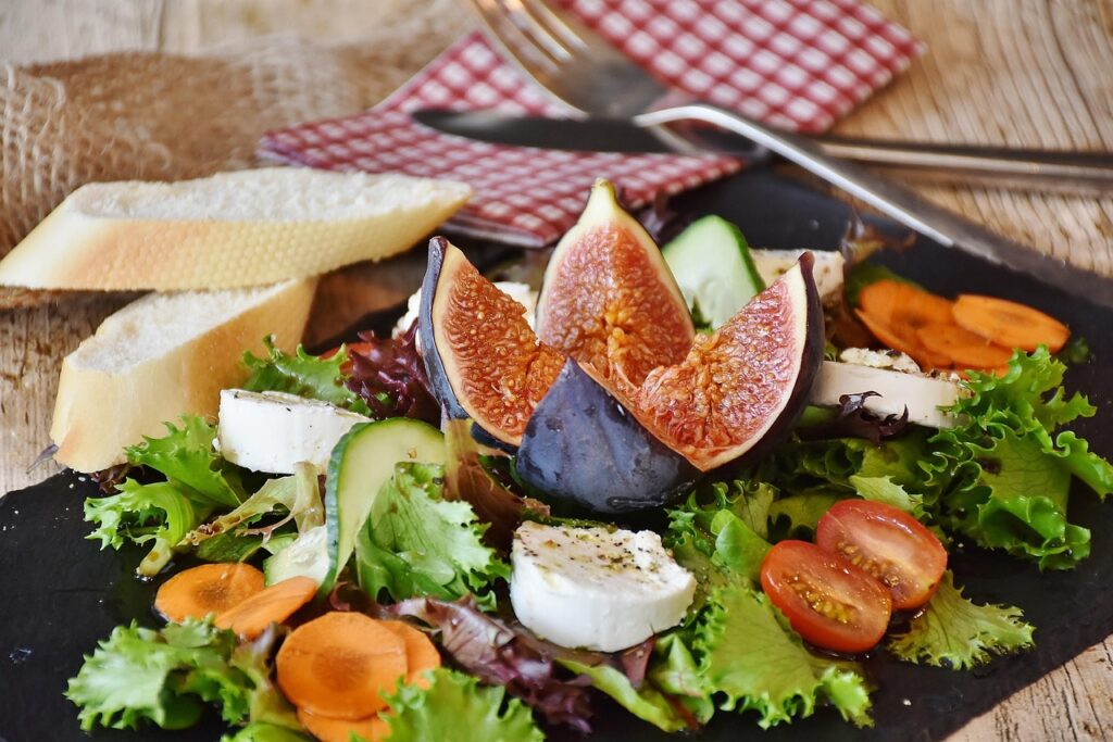 beautiful salad with fresh cheese, garlic bread, tomatoes, carrots, cocumber and fig.