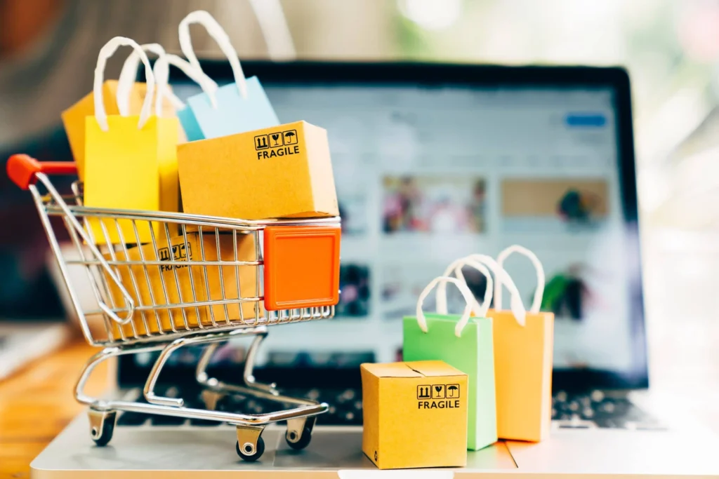 trolley with gifts infront of a laptop, represnting online shopping trends in 2026