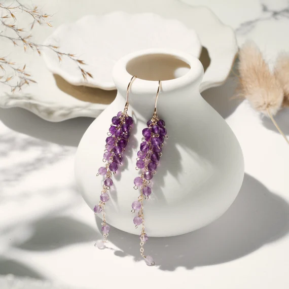 Genuine amethyst earrings in a gold setting, around a clay pot, promoting a sense of calm and spiritual balance.