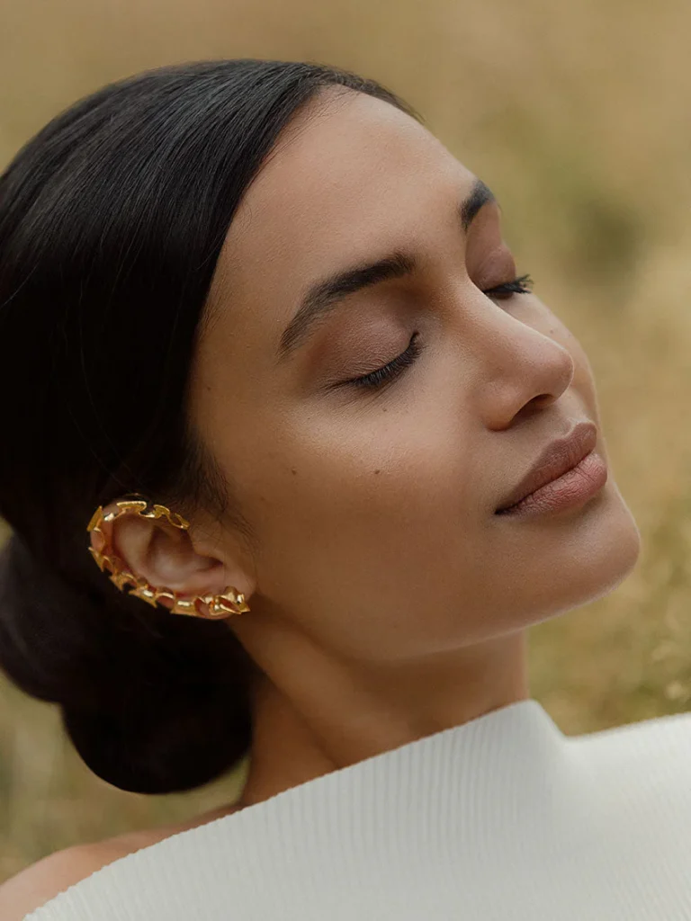 Silver crystal ear cuff wrapping around the ear cartilage, showcasing an edgy luxury style and peace acquired from wearing it.