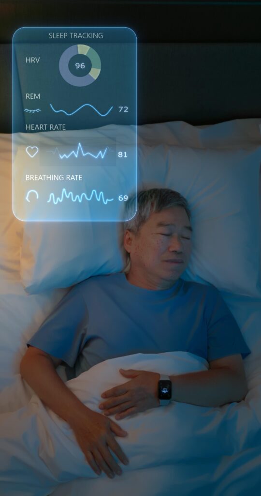 Sleep Tech: The Smart 2026 Bedroom Revolution for Deeper, Restorative Sleep. 5 An elderly Asian man sleeping in bed while wearing a smart watch tracker, featuring a digital overlay displaying vitals like HRV, REM sleep, heart rate, and breathing rate.