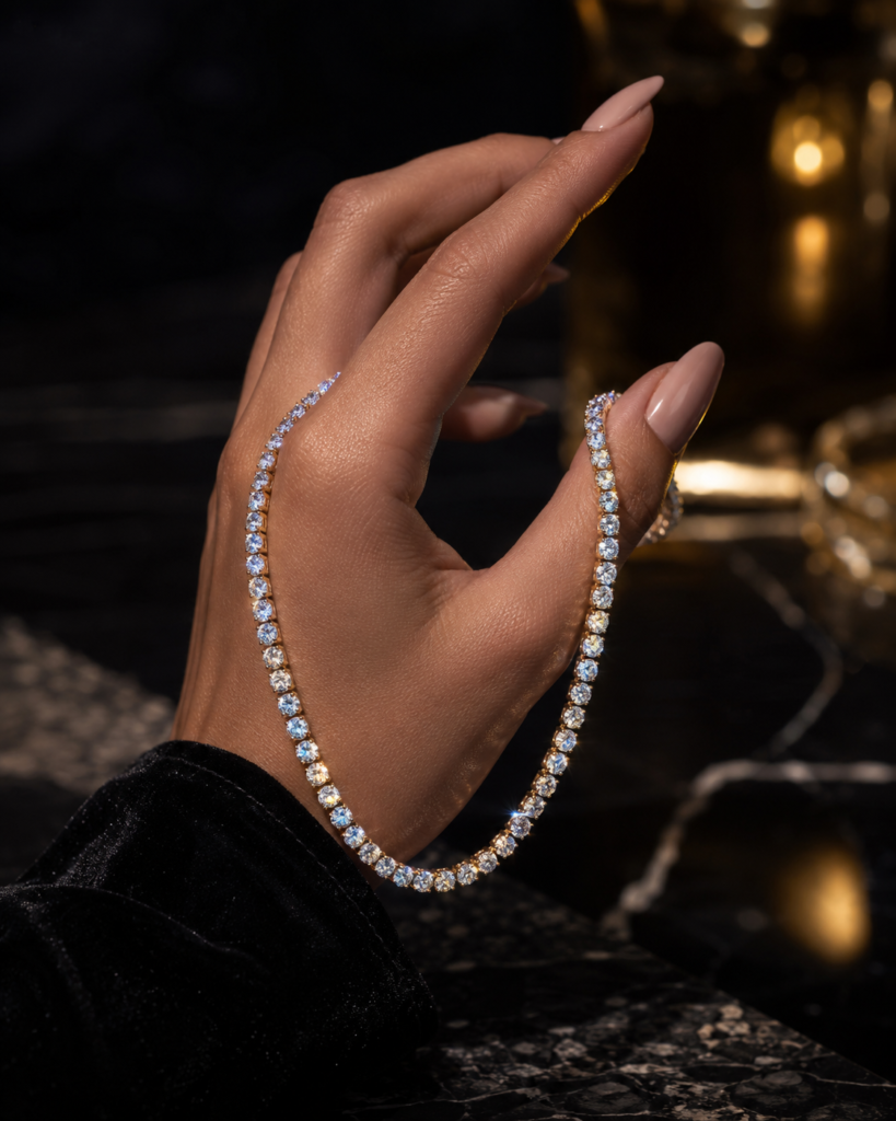 Moissanite tennis chain held by a model hand in a classy luxury setting, showing brilliant stones and an elegant gold chain design.